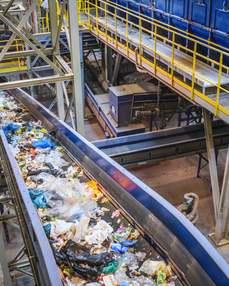 Plastics and waste moving on a conveyor inside a large sorting machine